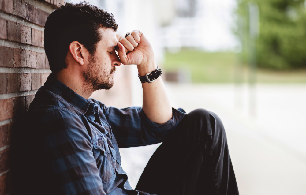 Lonely Depressed Person Sitting Near A Brick Wall With The Bible On His Lap