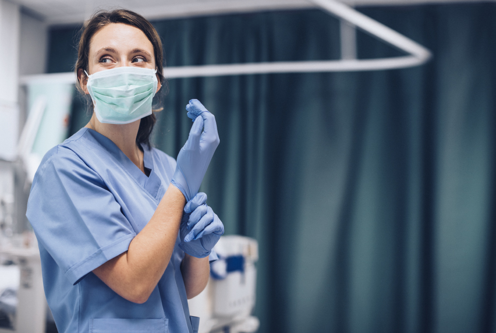 Female Nurse With A Mask Putting On Gloves Preparing To Cure Cor