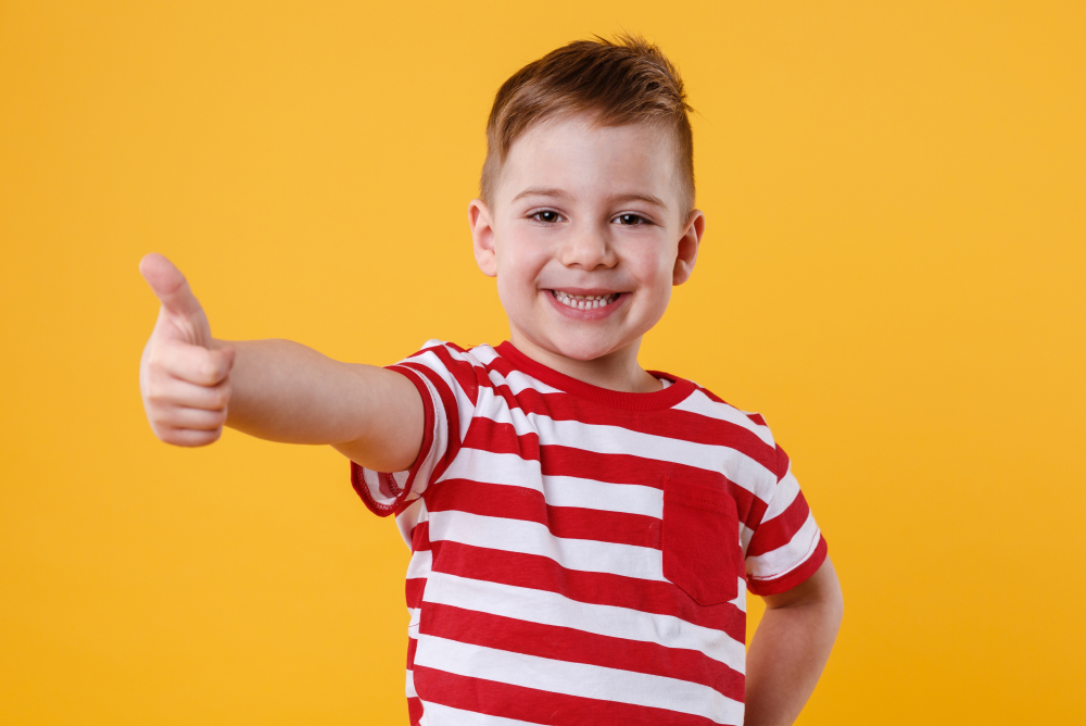 Portrait Of A Smiling Little Boy Showing Thumbs Up