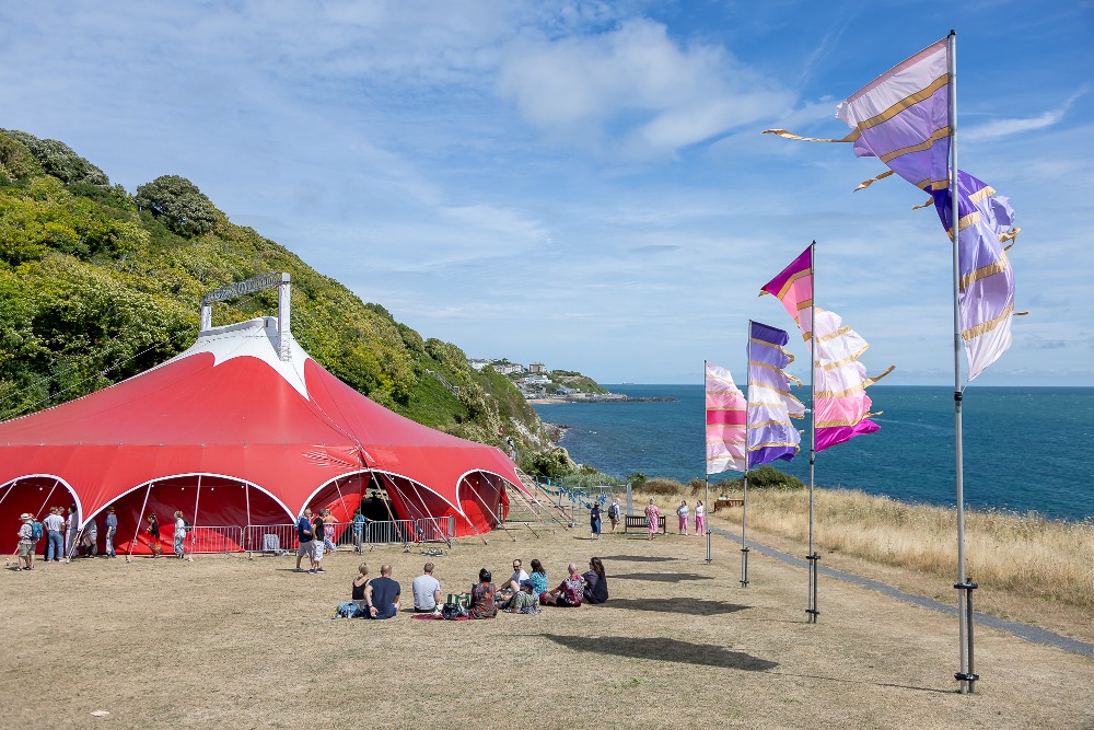 The intimate setting of a fringe festival tent, glowing under soft lights, symbolizing small-scale performances bursting with raw emotion