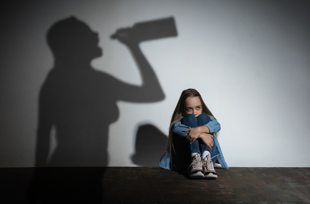 Domestic Violence, Abusing. Scared Little Caucasian Girl, Victim Sitting Close To White Wall With Shadow Of Angry Threatening Mother With Alcohol Addiction.