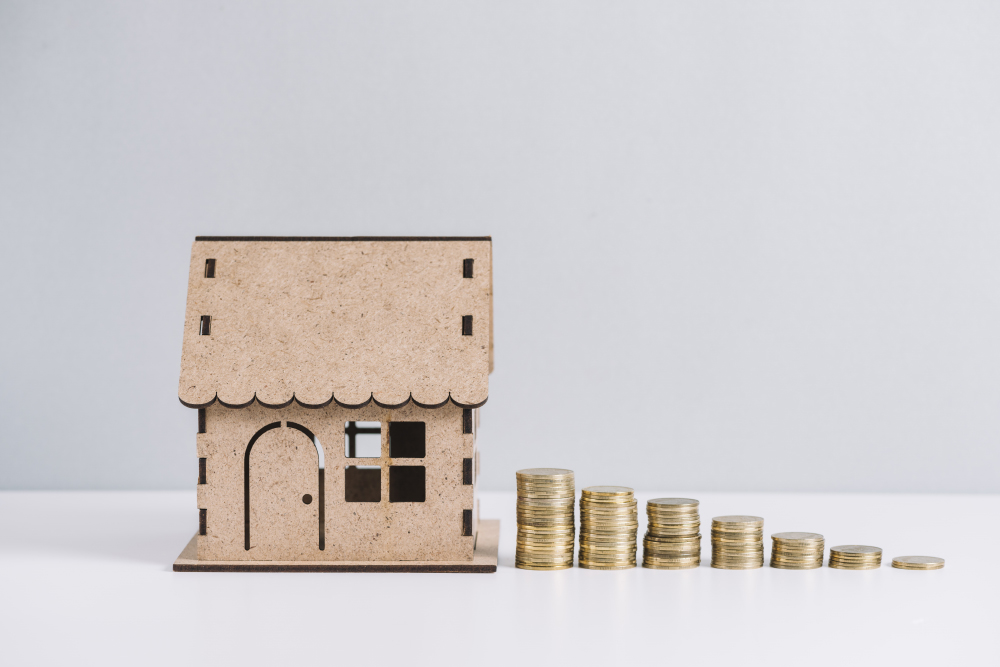 Stacked-coins-near-house-model-against-white-background