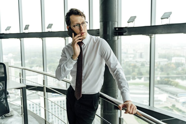 A professional-looking man in a white shirt talking on his phone.
