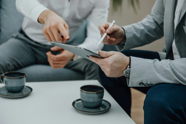 Two men sitting at a coffee table with a tablet.